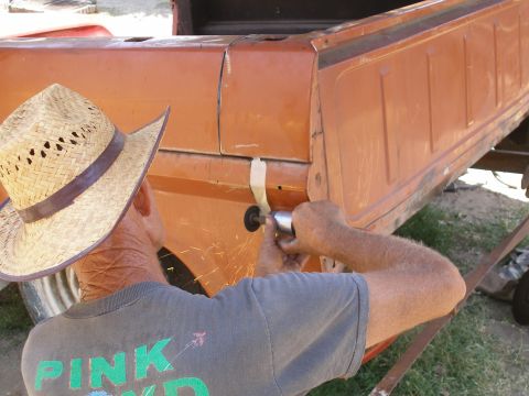 1969 Ford F-250 - Man grinding on the side of an orange truck bed, sparks flying.