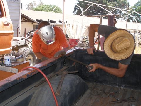 1969 Ford F-250 - Two men are working on the bed of a truck, one welding and the other using a tool.
