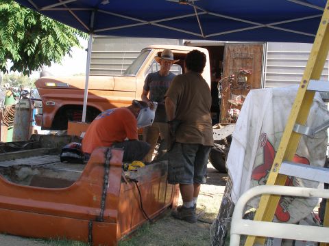 1969 Ford F-250 - Three men are welding and working on the bed of a 1969 Ford F-250 truck.