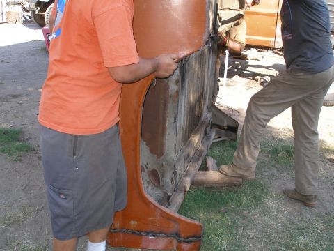1969 Ford F-250 - Workers attach an orange fender to a truck bed during a body swap.