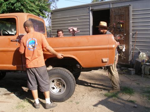 1969 Ford F-250 - Men are working on the bed of an orange pickup truck next to a trailer.