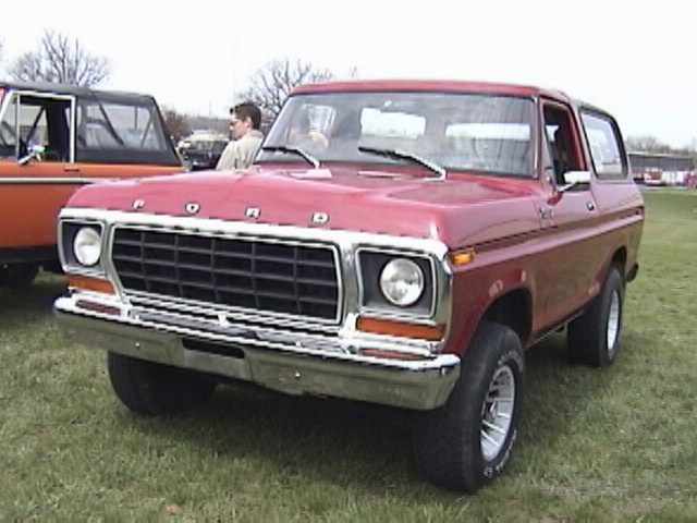 Red Ford Bronco with chrome grille and bumper, parked on grass