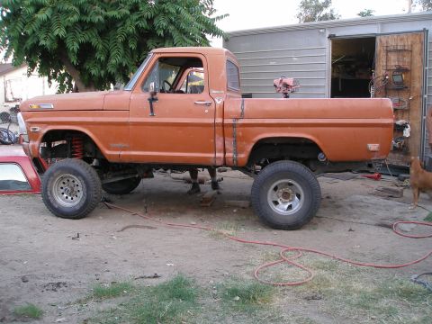 1969 Ford F-250 - This orange pickup truck features a lifted suspension and visible body modifications, suggesting it is not a stock 1969 Ford F-250.
