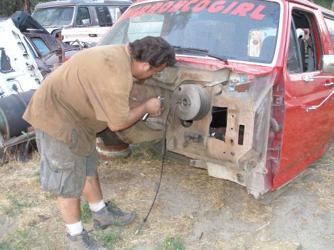 1969 Ford F-250 - Man works on the engine bay of a red truck. Other vehicles are visible in the background.