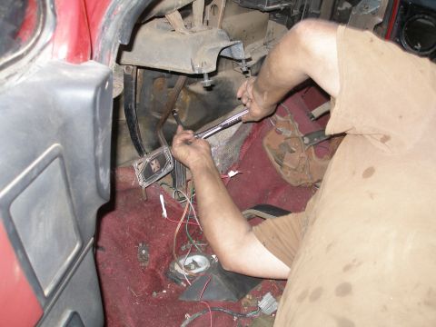 1969 Ford F-250 - A person works on the interior of a red vehicle, with visible wires and maroon carpet.