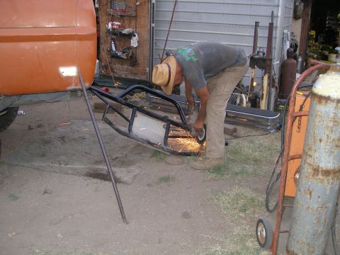 1969 Ford F-250 - A man works on a custom bumper for an orange truck, sparks flying from his grinder.