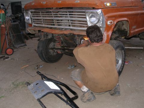 1969 Ford F-250 - A man welds on the front of an orange Ford truck, revealing a 1967 model year grille.