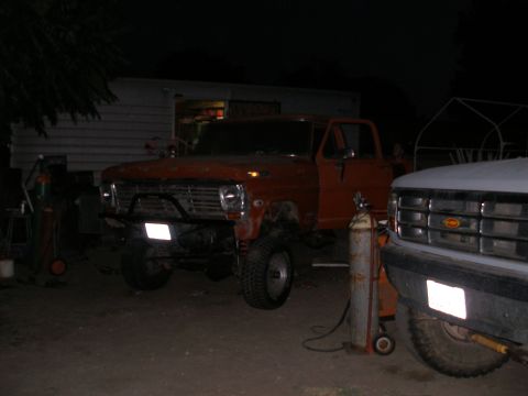 1969 Ford F-250 - An orange pickup truck is parked outside at night, with another truck partially visible to its right.