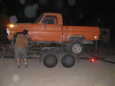 1969 Ford F-250 - This orange 1969 Ford F-250 pickup truck is being transported on a trailer at night.