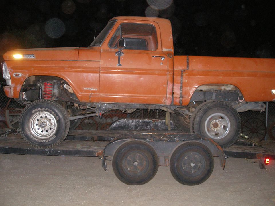 Orange pickup truck with lifted suspension on a trailer. Looks like a 1967 Ford F-100