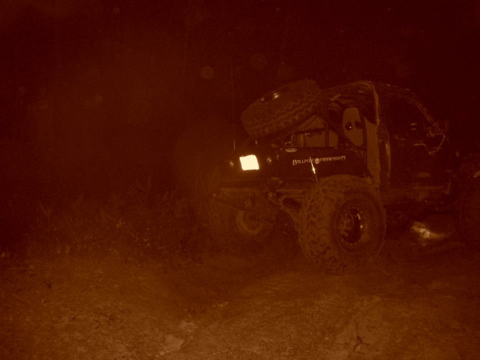 Off-road vehicle with spare tire on rear, driving in dusty conditions