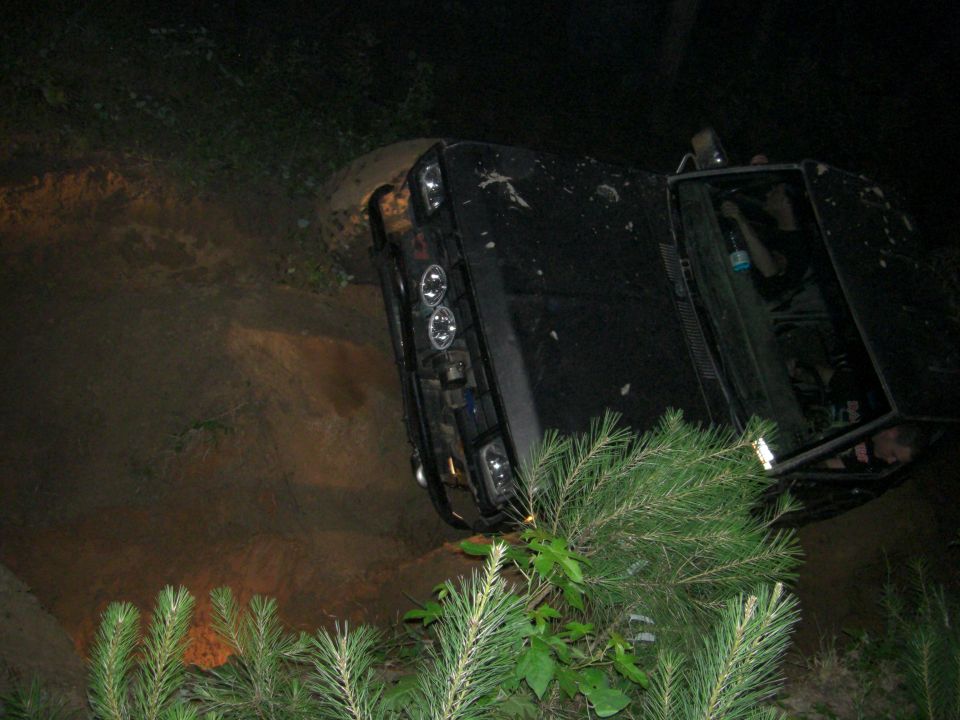 black SUV tipped on its side in dirt and brush