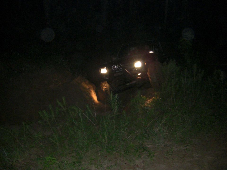 Off-road vehicle driving on a dirt path at night, headlights on