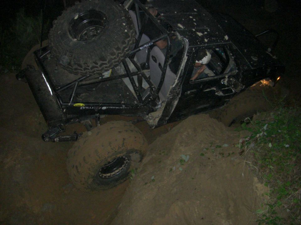 Off-road buggy with roll cage stuck in a dirt embankment at night