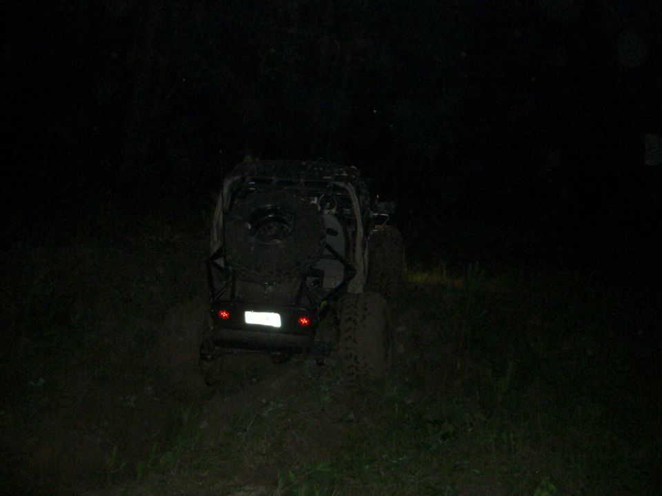 Off-road vehicle with spare tire on back, rear view at night