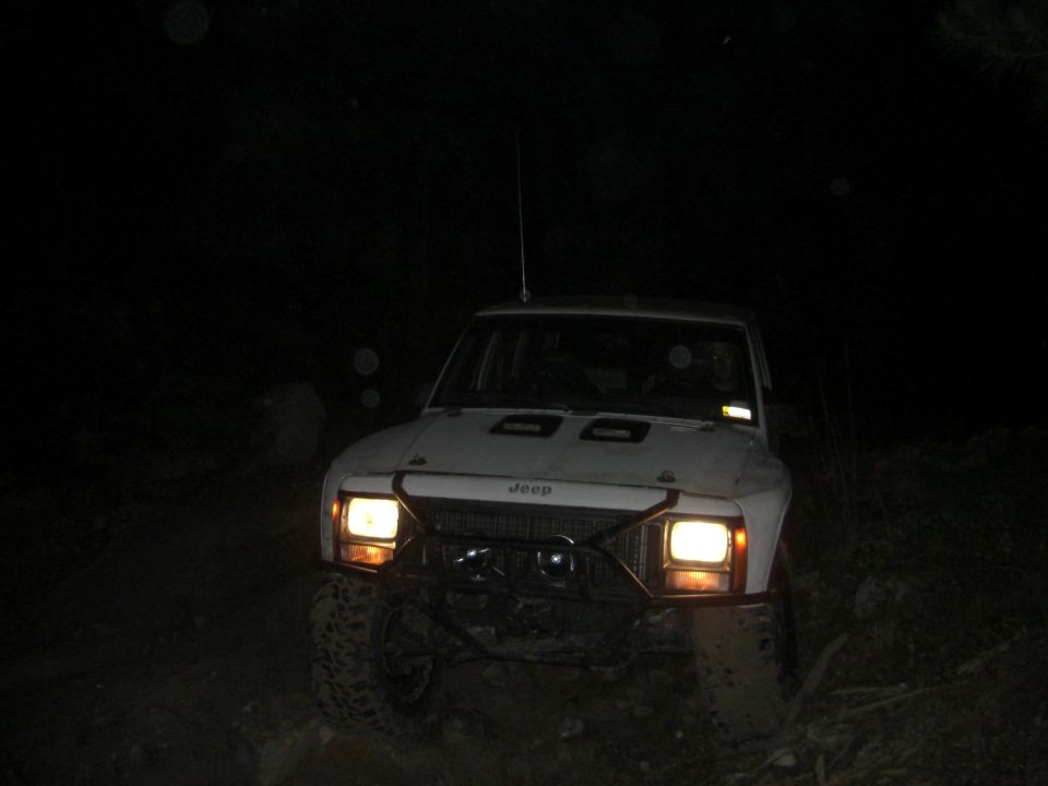 White Jeep Cherokee XJ with aftermarket bumper and hood vents at night
