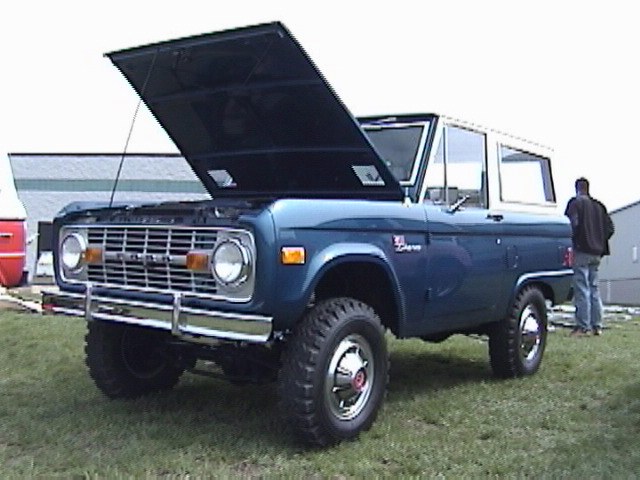 Blue Ford Bronco with hood open, chrome grille, and white roof