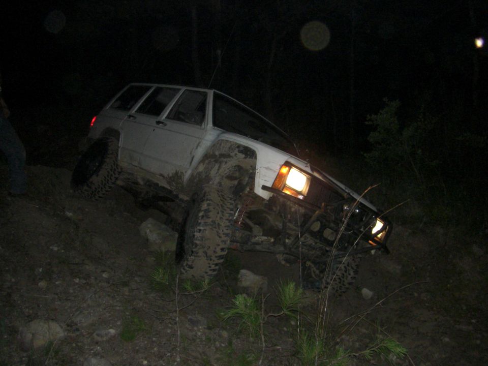 White SUV stuck on a muddy hill at night