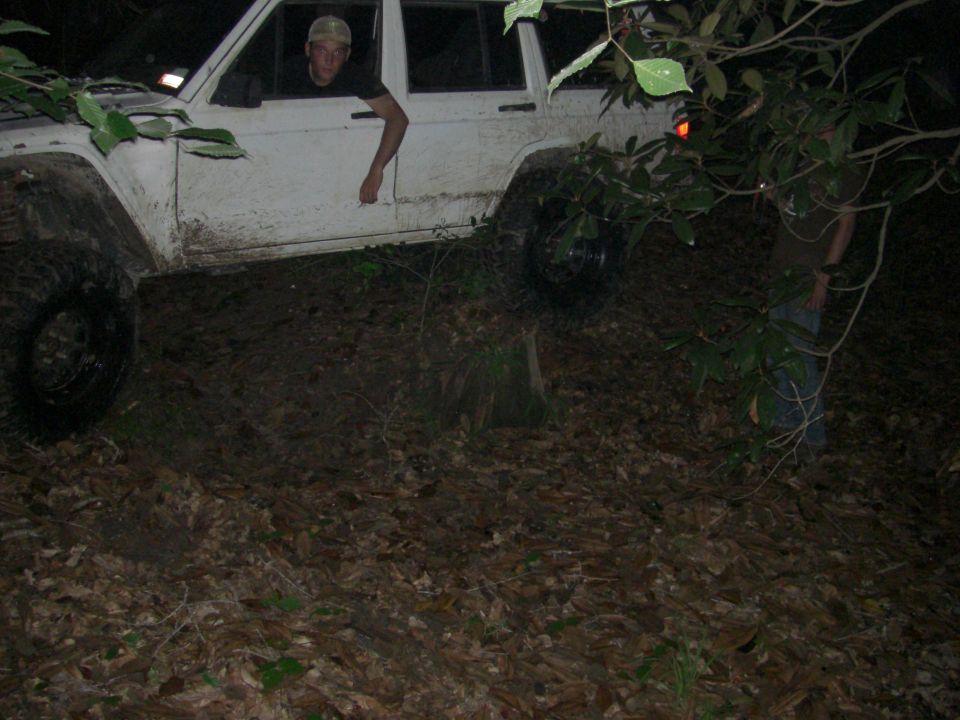 White SUV with large tires navigating muddy terrain at night