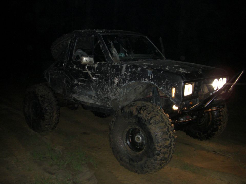 Black off-road SUV with large tires and aftermarket bumper at night