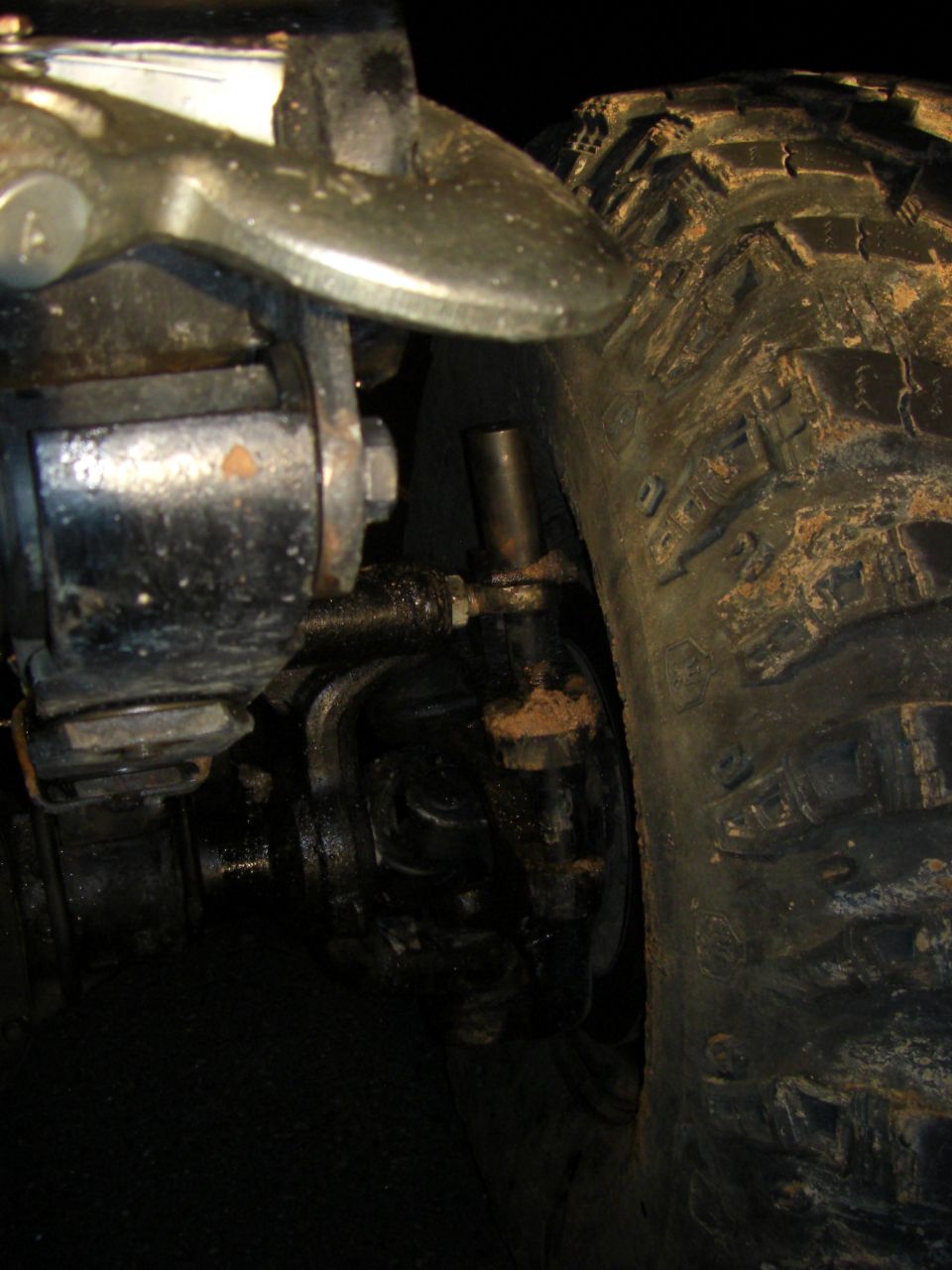 Close-up of a vehicle's front suspension and tire, showing mechanical components and tread