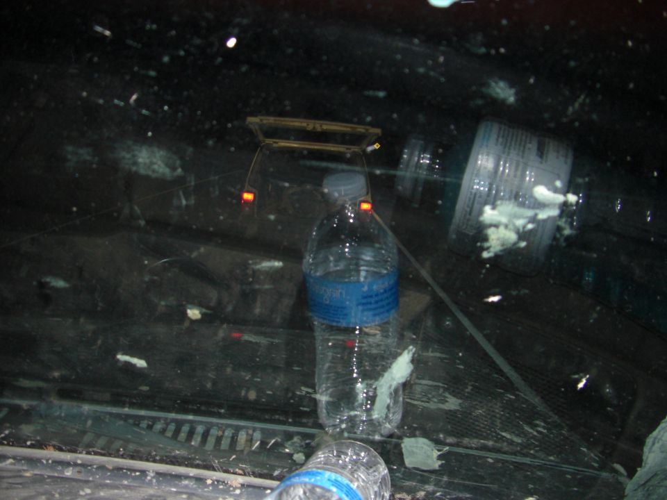 Interior view of a vehicle with water bottles and debris on the dashboard