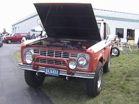 1995 Ford Bronco - This classic Ford Bronco is displayed with its hood open, revealing the engine bay. A second vehicle is visible in the background.