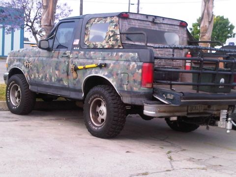 1986 Ford Bronco - This 1986 Ford Bronco is covered in camouflage and has an axe mounted to its side.