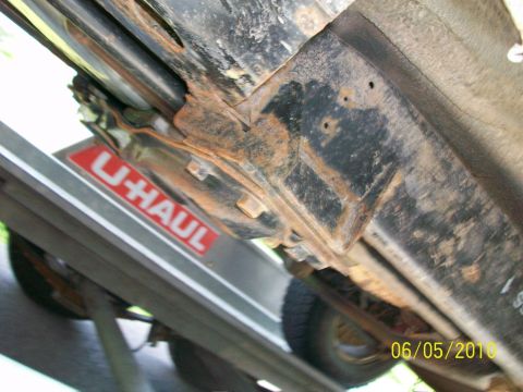 1999 Isuzu Vehicross - The vehicle's undercarriage is visible, resting on a U-Haul trailer, with visible rust on the frame.