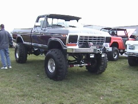 1995 Ford Bronco - This lifted pickup truck, likely from the late 1970s, is parked on a grassy field with other vehicles visible.