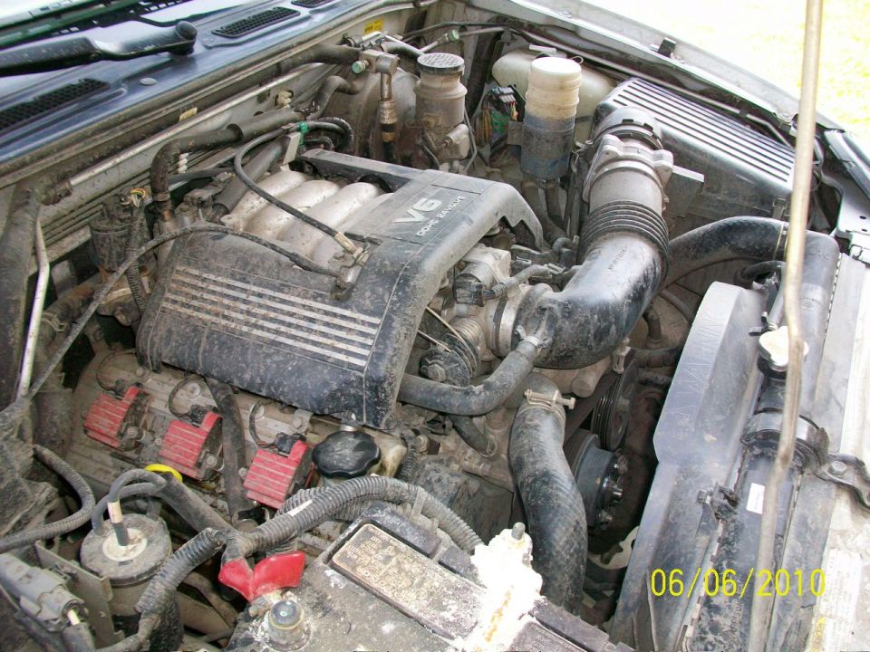 Engine bay with V6 DOHC engine, air intake, radiator, and battery visible. Watermark reads 06/06/2010