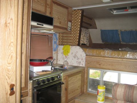 1978 Ford Bronco - The interior of a camper features a kitchenette with a sink and stove, along with a sleeping area.