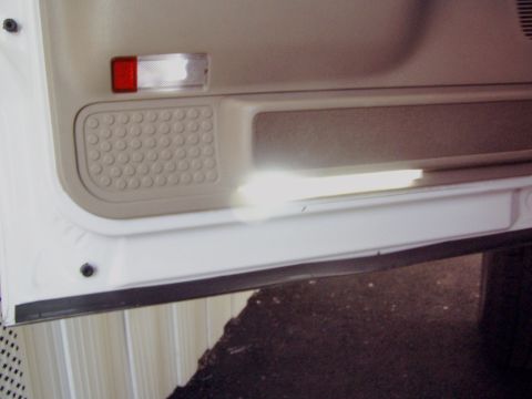 2001 Ford Excursion - Close-up of a vehicle's interior door panel, showing a reflector and speaker grille.