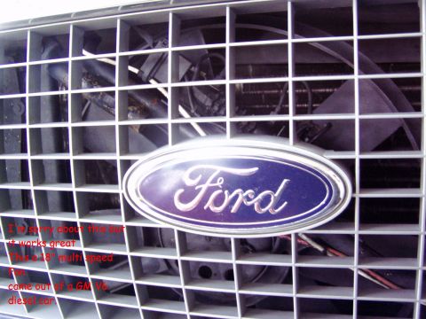2001 Ford Excursion - Close-up of a Ford emblem on a vehicle's front grille, with visible fan components.
