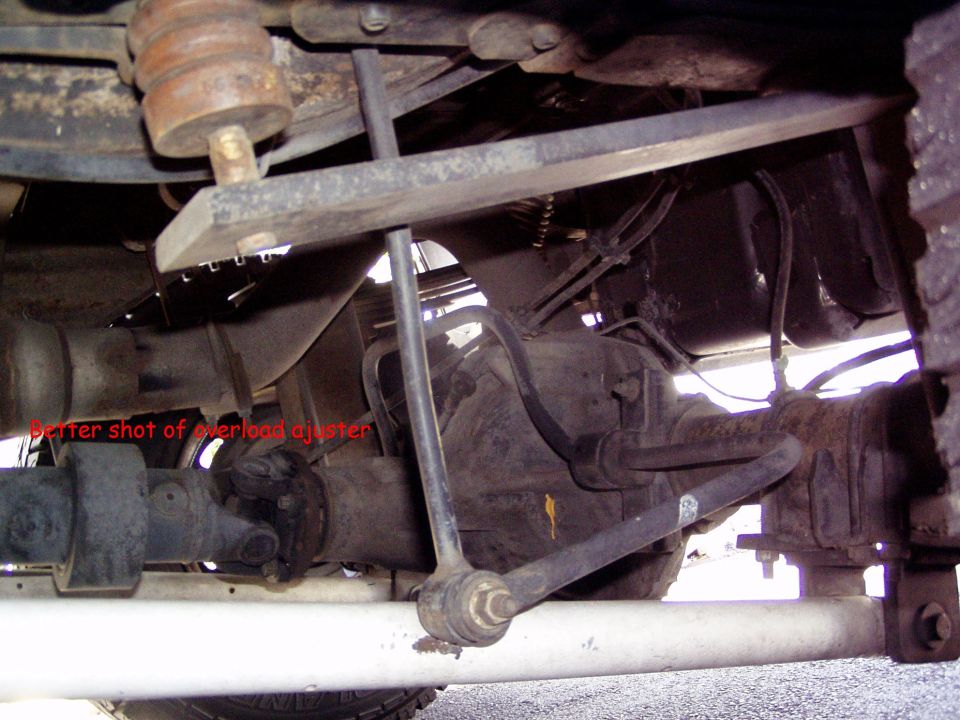Underside view of a vehicle's rear axle and suspension with visible rust and wear