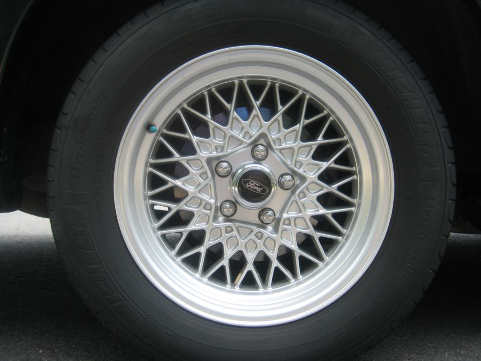 Close-up of a silver mesh wheel with a Ford logo center cap and a black tire