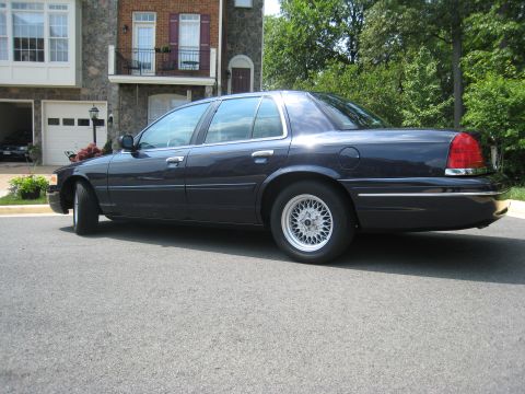 1999 Ford Crown Victoria - A dark blue 1999 Ford Crown Victoria sedan is parked on a residential street.