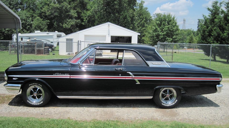 Black 1964 Ford Fairlane 500 coupe with red interior and chrome trim. BFGoodrich Radial T/A tires