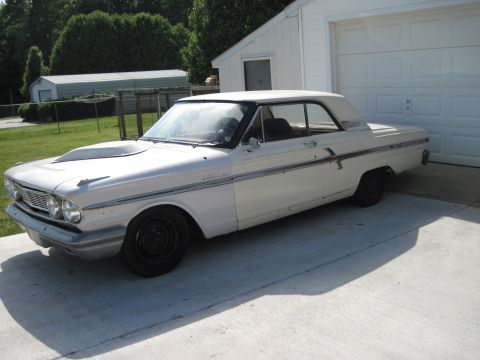 1992 Ford Mustang - A vintage white Ford Fairlane sits parked in front of a garage.