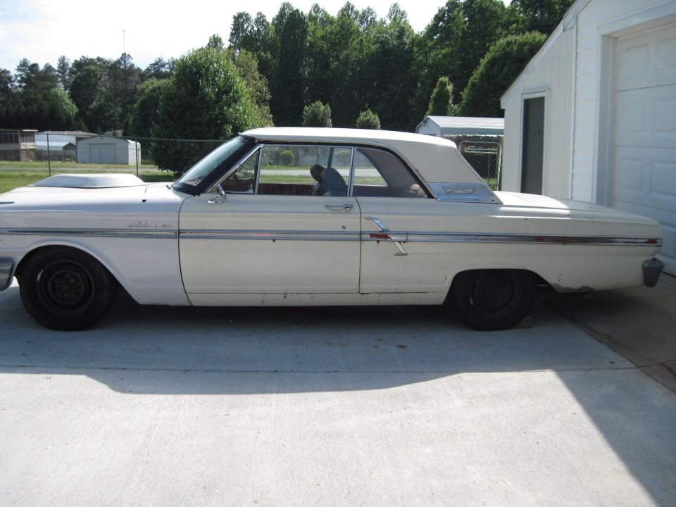 Side view of a white 1964 Ford Fairlane with a hood scoop and black wheels