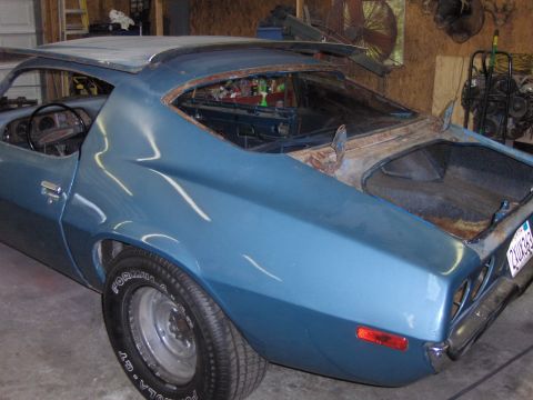 1970 Chevrolet Camaro - This 1970 Chevrolet Camaro is seen in a garage, undergoing restoration with visible rust around the windows and trunk area.