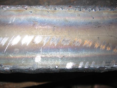 1989 Ford Bronco - Close-up of a metal beam showing evidence of welding and surface damage.