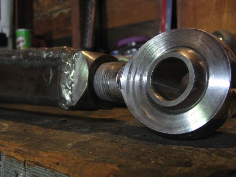1989 Ford Bronco - A close-up view of a metal linkage part resting on a wooden surface.