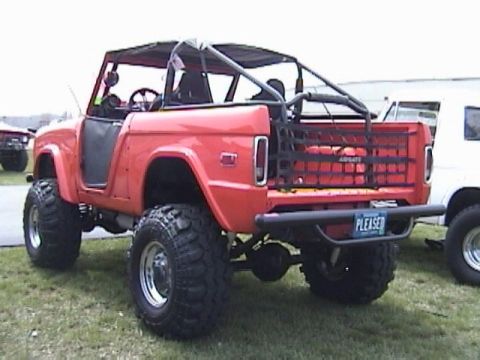 1995 Ford Bronco - This modified Ford Bronco features a custom rear rack and off-road tires, parked outdoors.