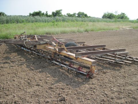 1993 Ford Bronco - A piece of farm equipment sits in a tilled field under a bright sky.