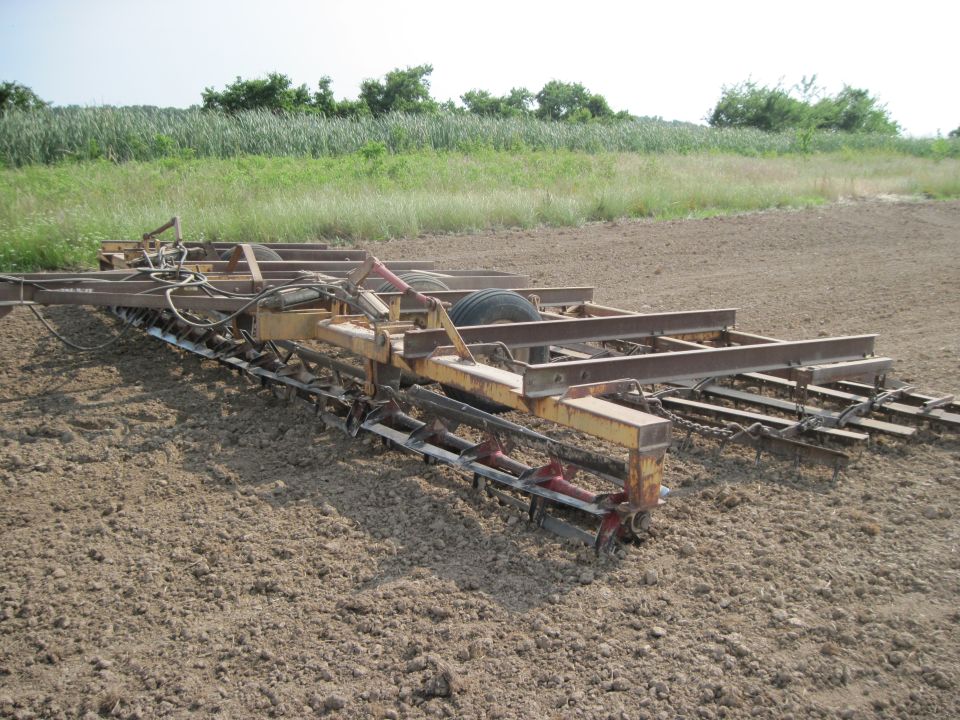 farm implement with tines and wheels in a field