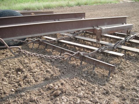 1993 Ford Bronco - Agricultural equipment with chains and tines is shown in a dirt field.