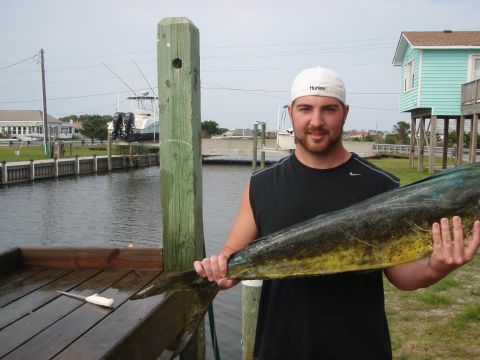 1995 Ford Bronco - Man proudly displays a large dolphin fish caught near a dock with boats in the water.