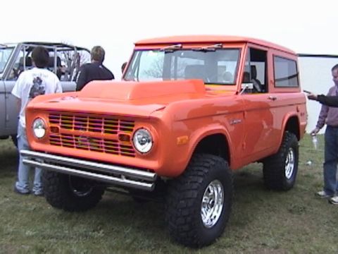 1995 Ford Bronco - This orange Ford Bronco features a prominent hood scoop and off-road tires.