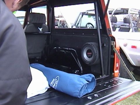 1995 Ford Bronco - The interior of a 1995 Ford Bronco shows a custom subwoofer installation and a blue Ford branded item in the cargo area.